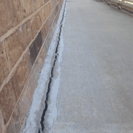 This expansion joint was allowing water running down the brick and under the slab.  This creates softening of the fill soil and settling of the sidewalk. 